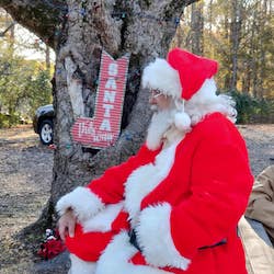 Santa Claus sitting beside a tree